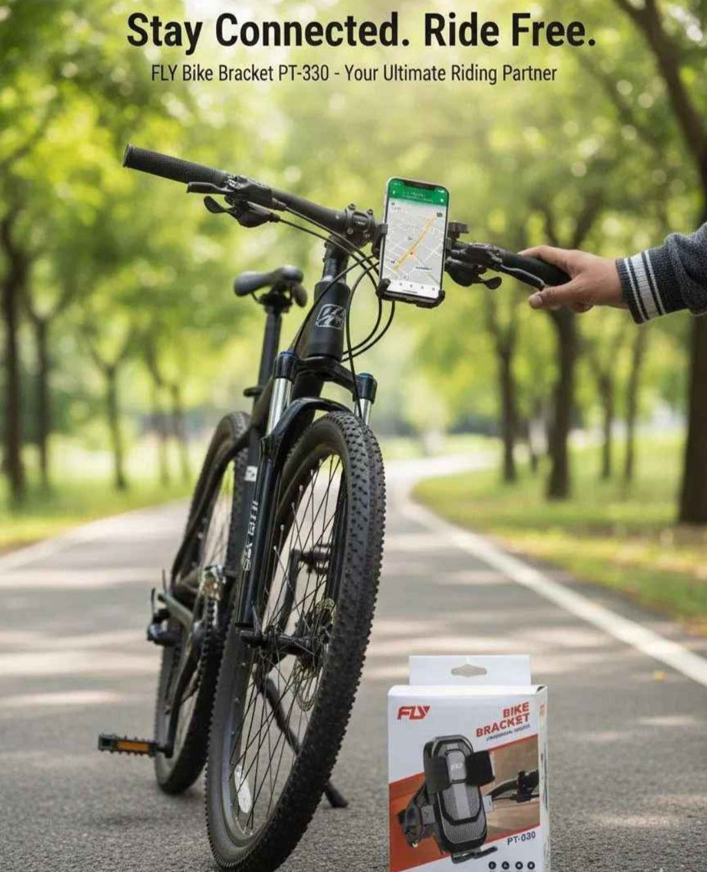 Bicycle with a phone mounted on the handlebar, next to a box of FLY bike bracket, in a park setting.