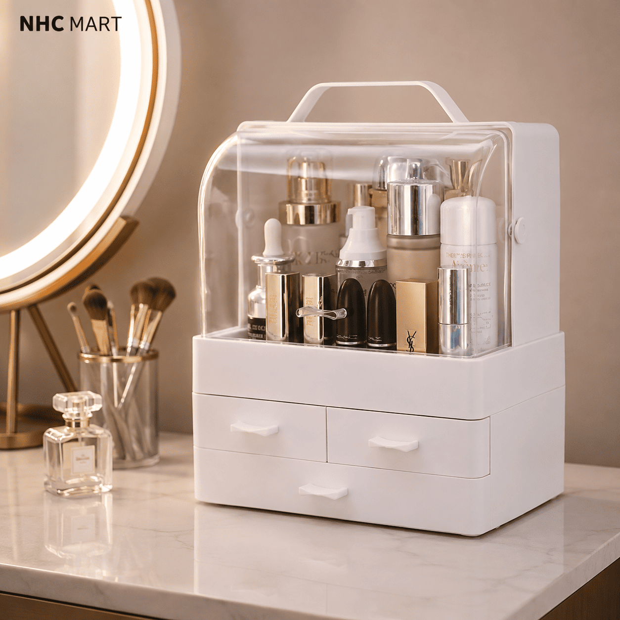White makeup organizer with a clear plastic top cover and three drawers, shown on a marble vanity counter with cosmetics inside. A round mirror and perfume bottle are visible in the background.