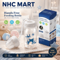 NHC Mart Hands Free Feeding Bottle set, featuring a 150ml clear baby bottle with a blue deer illustration, a white breast pump, and its blue retail packaging box, displayed on a cozy blanket with baby toys in the background.