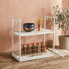 White metal rack with shelves holding kitchen items against a pink wall.