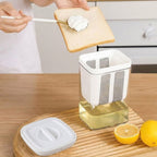 Person spreading cream on toast with a kitchen appliance on a wooden surface