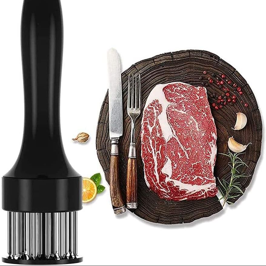 Meat tenderizer on the left with a steak on a wooden board with cutlery and spices on the right.